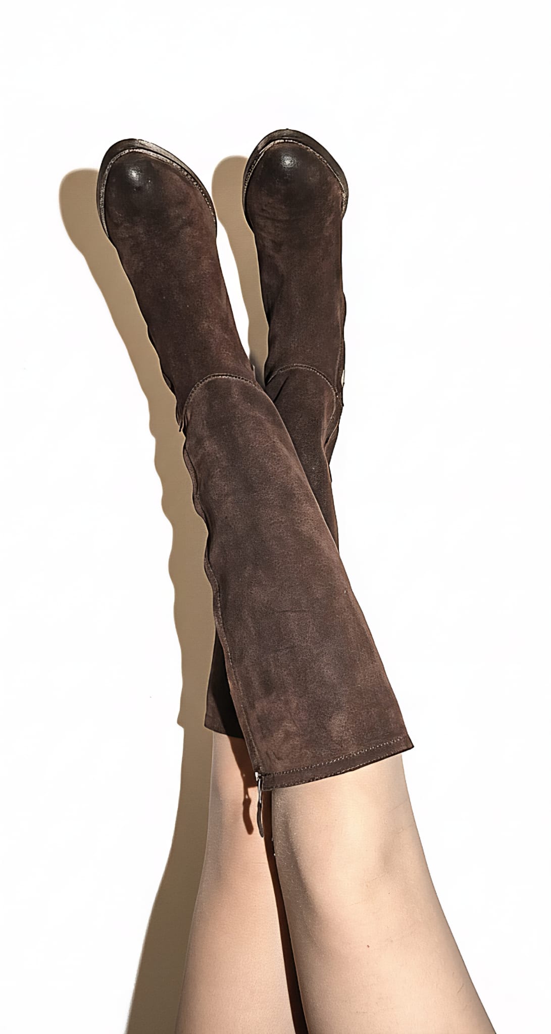 Brown knee-high boots worn by a person on a white background